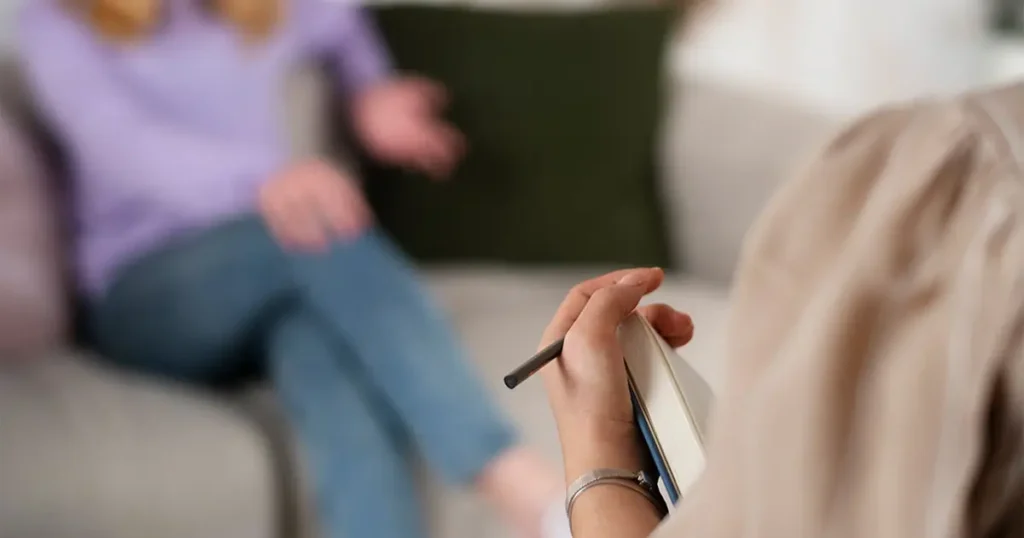Consulenza psicologica a domicilio in Lombardia: una psicoterapeuta prende appunti durante una seduta di supporto clinico svolta con empatia e riservatezza a casa della paziente.