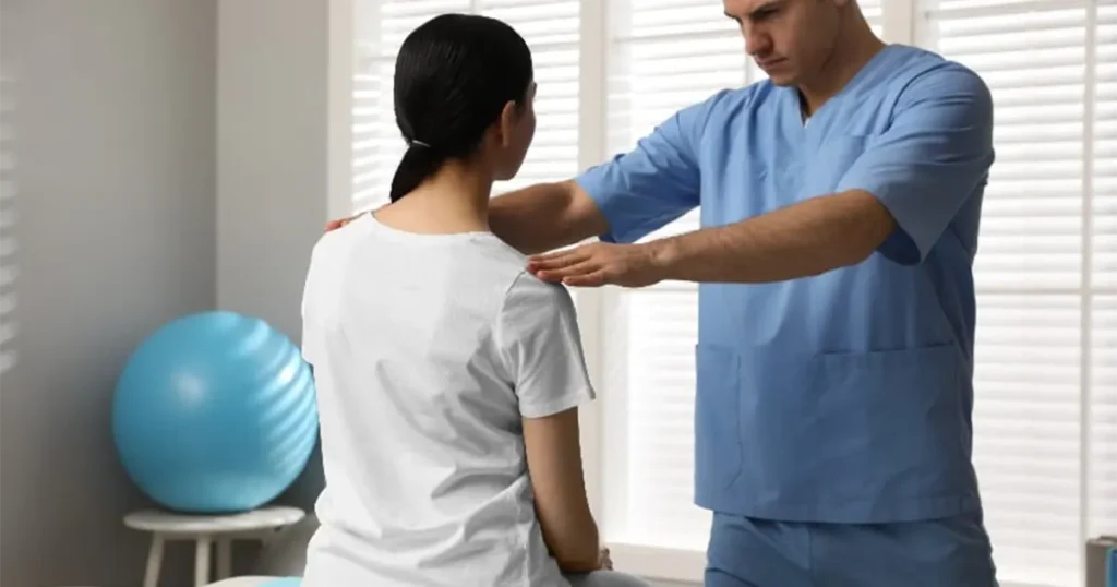 Visita fisiatrica a domicilio in Lombardia: un medico fisiatra esegue una valutazione posturale e ortopedica della schiena e delle spalle a una paziente.