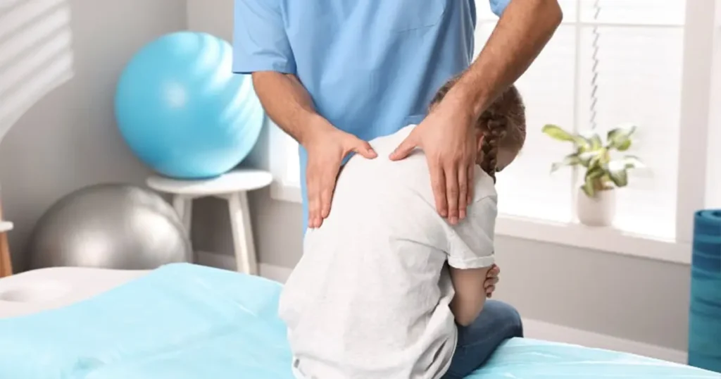 Visita osteopatica a domicilio in Lombardia: un professionista esegue una valutazione della colonna vertebrale e della postura su una paziente pediatrica direttamente a casa.